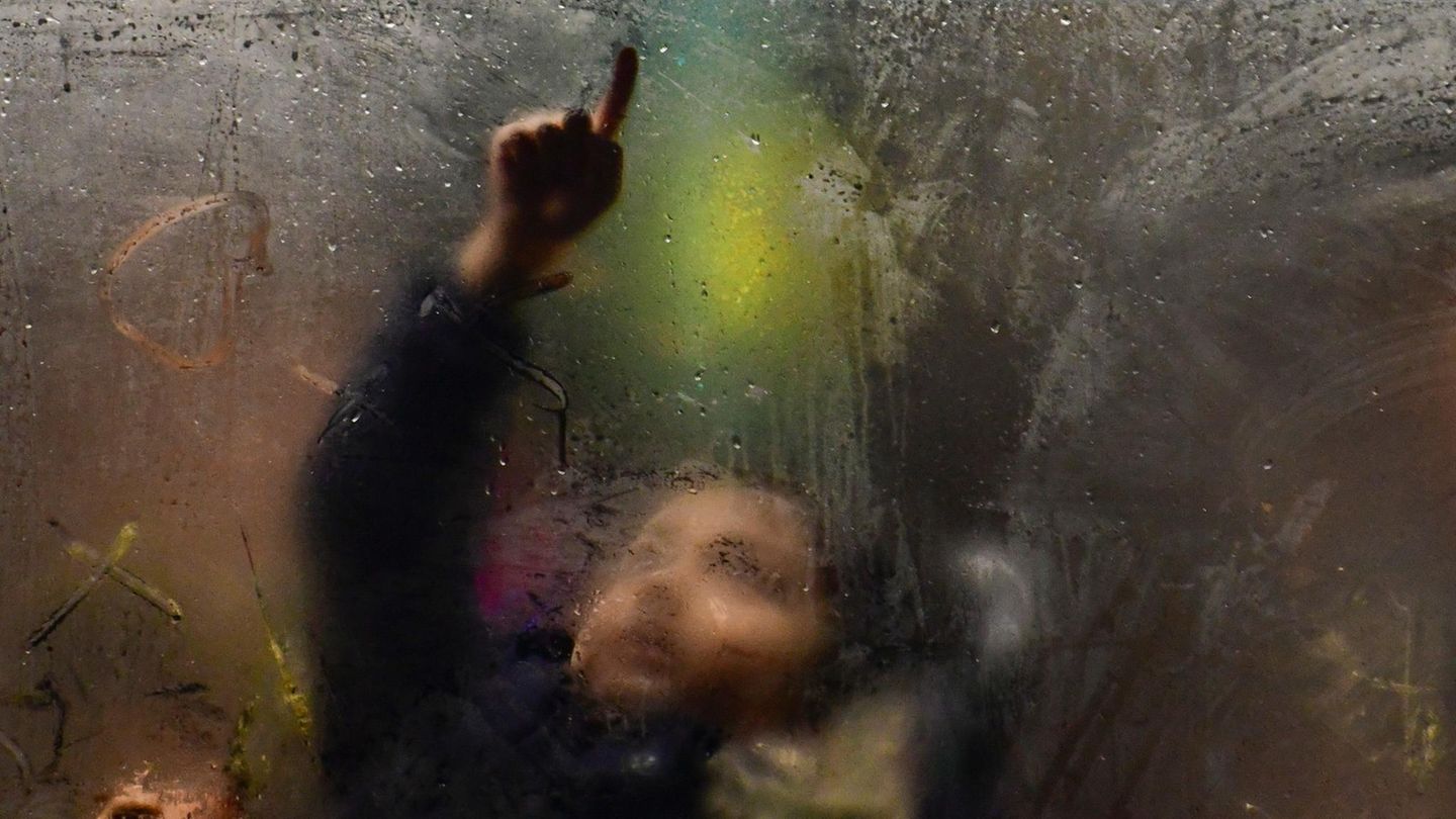 Kind im Bus zeichnet mit dem Finger auf beschlagene Scheibe