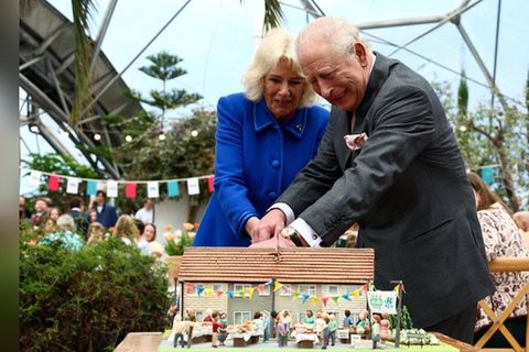 Königin Camilla und König Charles kämpfen sich mit einem Schwert durch eine Torte.
