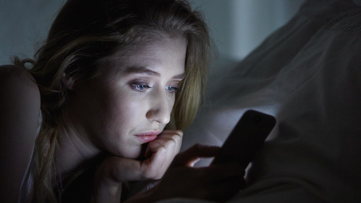 Thema Affäre: Eine Frau schaut im Dunkeln traurig auf ein Handy