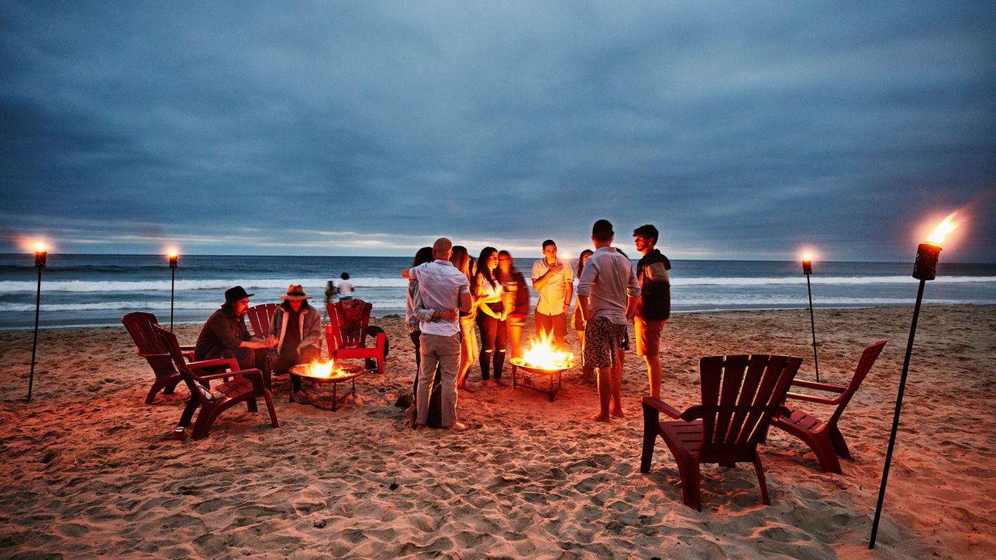 Eine Gruppe Menschen grillt in der Abenddämmerung am Strand