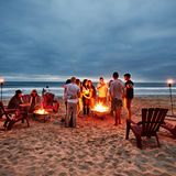 Eine Gruppe Menschen grillt in der Abenddämmerung am Strand