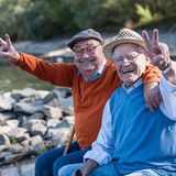 Zwei ältere Männer lachen in die Kamera und machen das Victory-Zeichen