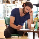 Ein Mann sitzt an einem Tisch und scheibt einen Brief