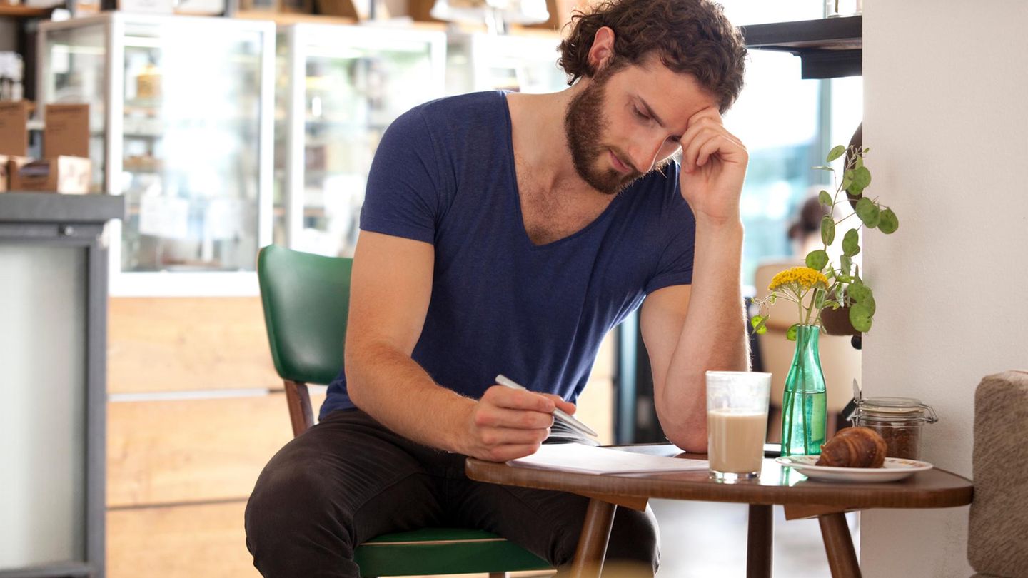 Ein Mann sitzt an einem Tisch und scheibt einen Brief