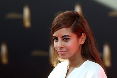 Collien Fernandes steht in weißem Kostüm auf einem Roten Teppich