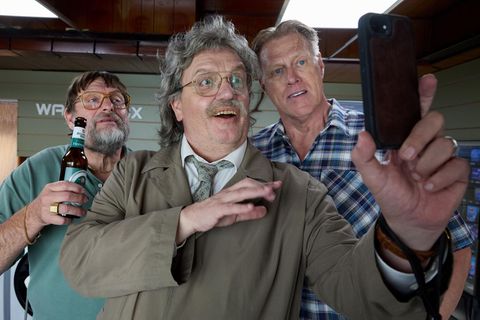 Horst Schlämmer steht mit zwei Männern und schaut in ein Handy