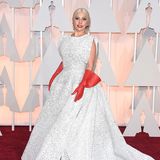 Lady Gaga in einem weißen Abendkleid mit roten Handschuhen