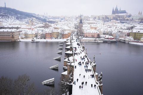 Menschen überqueren die mittelalterliche Karlsbrücke nach starkem Schneefall. Foto: Petr David Josek/AP/dpa