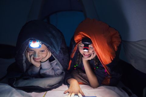 Stirnlampen für Kinder: Zwei Schulkinder beim nächtlichen Lesen