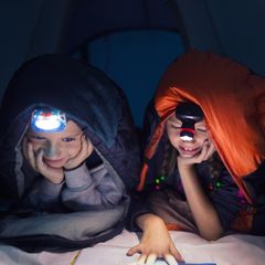 Stirnlampen für Kinder: Zwei Schulkinder beim nächtlichen Lesen