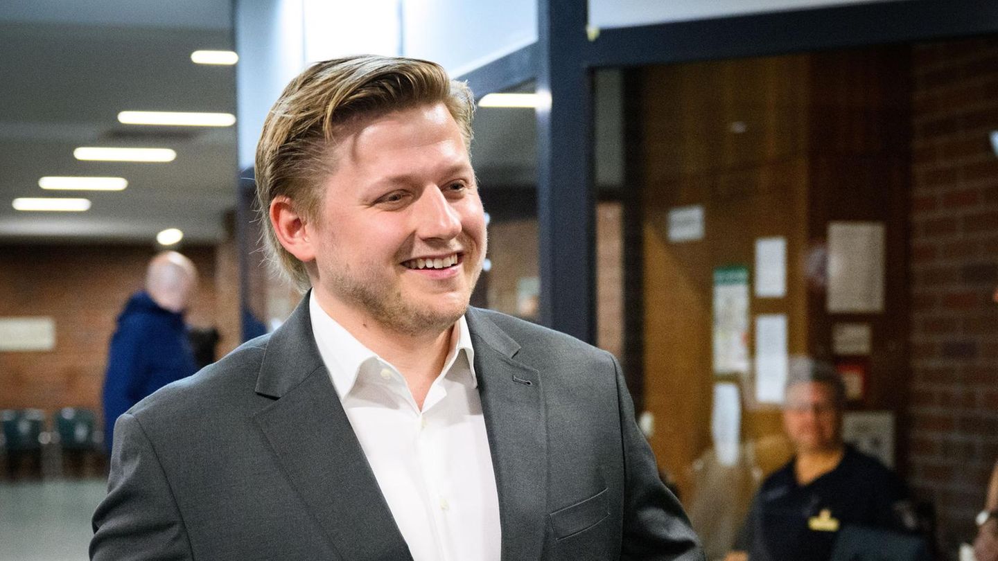 Sebastian Hotz alias El Hotzo lächelt auf einem Gerichtsflur