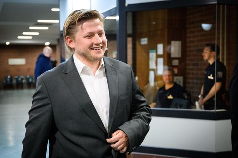 Sebastian Hotz alias El Hotzo lächelt auf einem Gerichtsflur