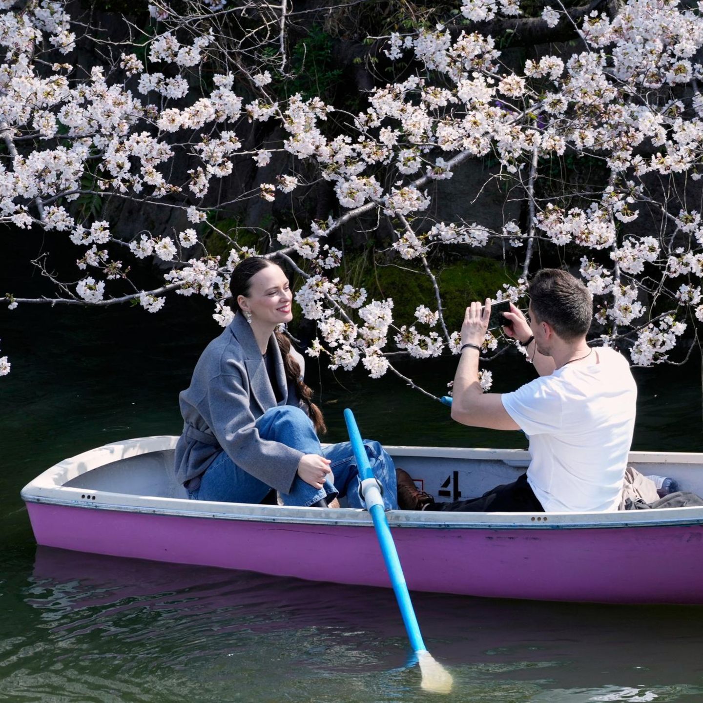 Tokio, Japan. Na, wer ist schöner: die junge Frau oder die Kirschblüte? Bei der Bootstour am Chidorigafuchi-Palastgraben hält der Fotograf beider Schönheit fest.