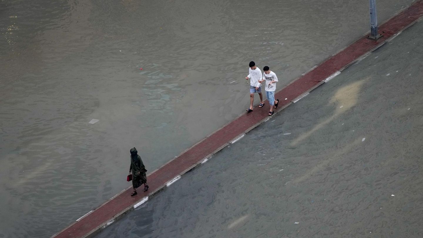Dubai, Vereinigte Arabische Emirate. In der Wüste fällt kein Regen? Von wegen! Nach heftigen Regenfällen nutzen Fußgänger den Fahrbahnteiler entlang einer überfluteten Straße, um trockenen Fußes ans Ziel zu kommen – als Laufsteg