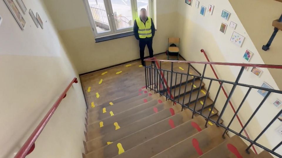 Ein Sicherheitsdienst-Mitarbeiter steht an einer Schultreppe.