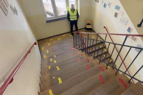 Ein Sicherheitsdienst-Mitarbeiter steht an einer Schultreppe.