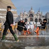 Menschen am überfluteten Markusplatz in Venedig