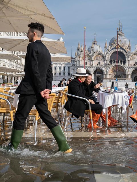 Menschen am überfluteten Markusplatz in Venedig