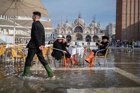 Menschen am überfluteten Markusplatz in Venedig