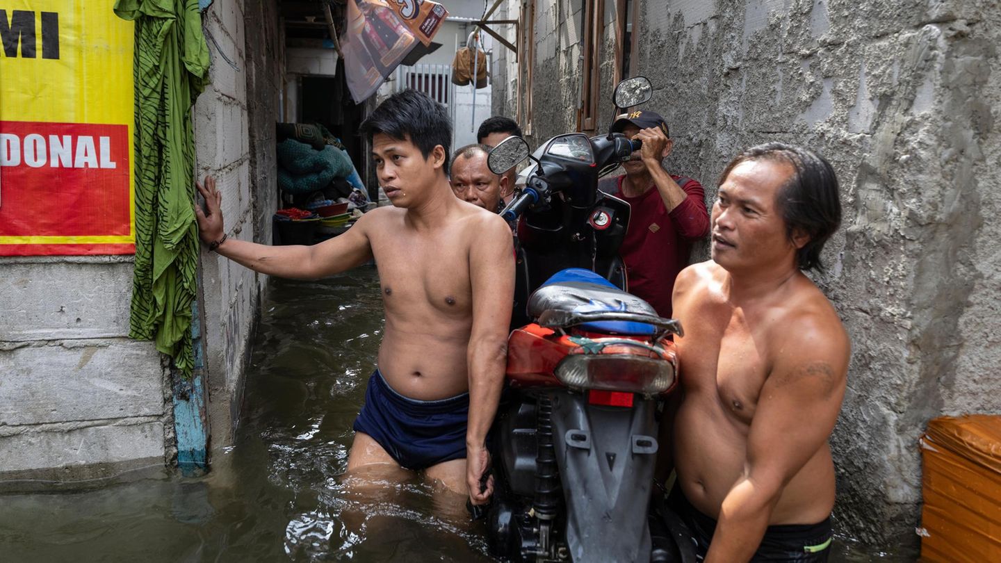 Männer tragen einen Roller durchs Wasser