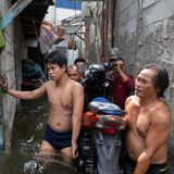 Männer tragen einen Roller durchs Wasser