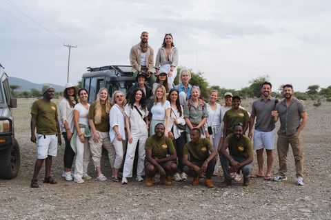 Eine Reisegruppe posiert vor einem Jeep