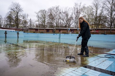 Diana Reimann, Badleiterin vom Sommerbad Humboldthain der Berliner Bäder-Betriebe, reinigt die Fliesen im Schwimmbecken. Foto: C