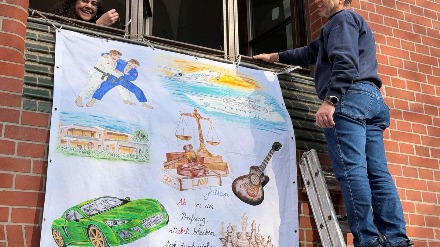 Lorans (l) und Marmik Yedgarian hängen ein Abiturplakat für die Abschlussprüfung ihres 19-jährigen Sohnes Julian in Wiesbaden au