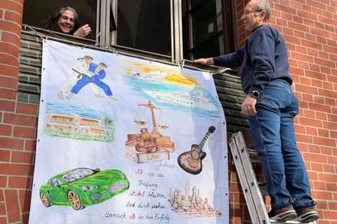 Lorans (l) und Marmik Yedgarian hängen ein Abiturplakat für die Abschlussprüfung ihres 19-jährigen Sohnes Julian in Wiesbaden au