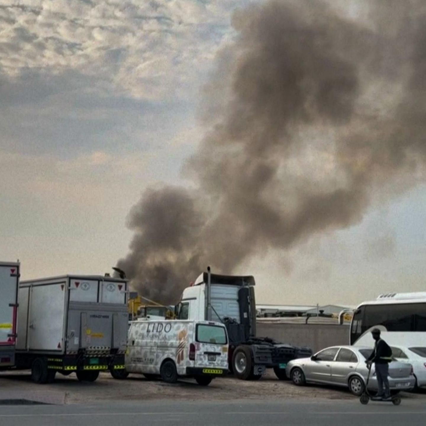 Rauchwolke am Himmel über abgestellten LKW