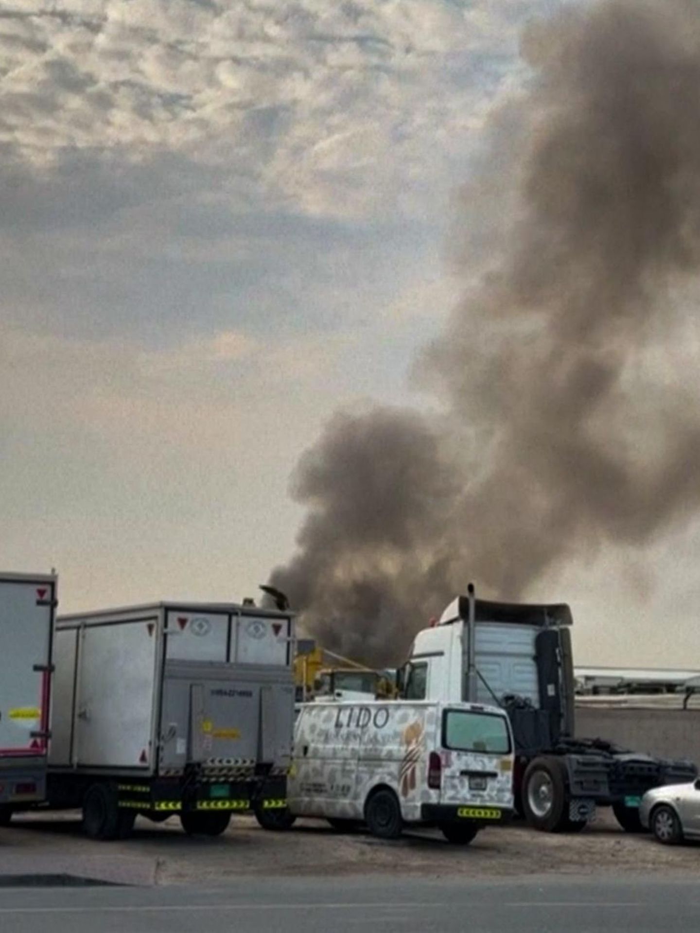 Rauchwolke am Himmel über abgestellten LKW