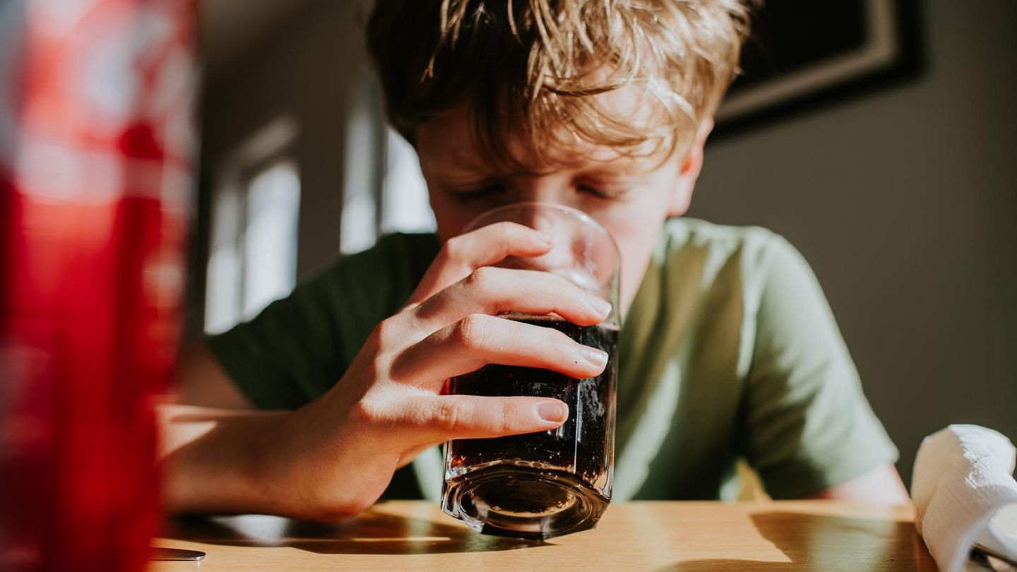 Ein Junge trinkt Cola aus einem Glas