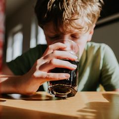 Ein Junge trinkt Cola aus einem Glas