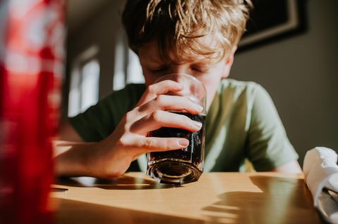 Ein Junge trinkt Cola aus einem Glas