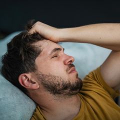 Mann mit Kopfschmerzen liegt auf Sofa