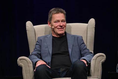 Hans Königsmann sitzt in einem Sessel auf einer Bühne