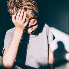 Migräne bei Kindern: Ein Schulkind greift sich an den Kopf