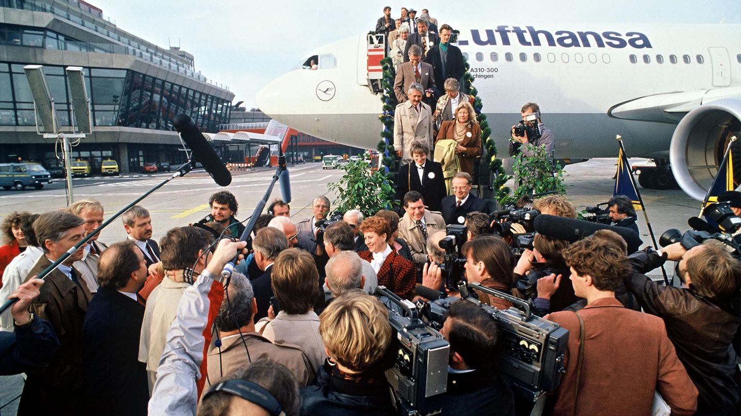 Passagiere steigen aus einer Lufthansamaschine und werden von Kameraleuten erwartet