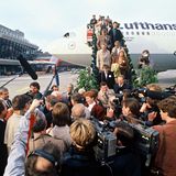 Passagiere steigen aus einer Lufthansamaschine und werden von Kameraleuten erwartet