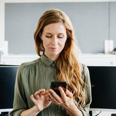 Eine Frau bedient im Bürpo ihr iPhone