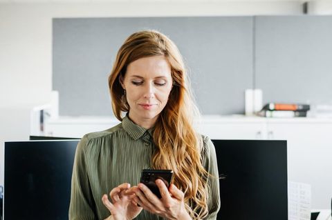 Eine Frau bedient im Bürpo ihr iPhone