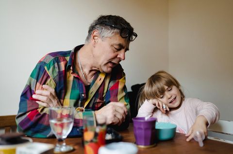Erziehung: Großvater sitzt mit Enkeltochter am Tisch