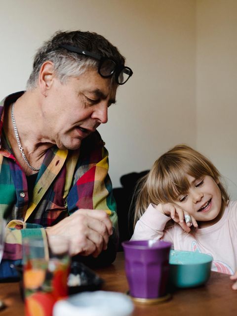Erziehung: Großvater sitzt mit Enkeltochter am Tisch