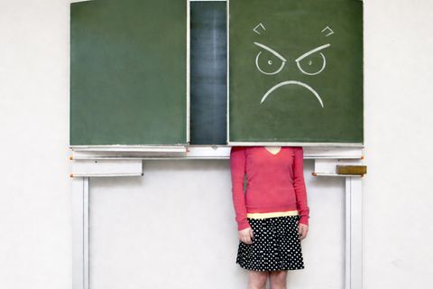 Eine frustrierte Lehrerin versteckt sich hinter einer Tafelklappe