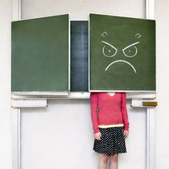 Eine frustrierte Lehrerin versteckt sich hinter einer Tafelklappe
