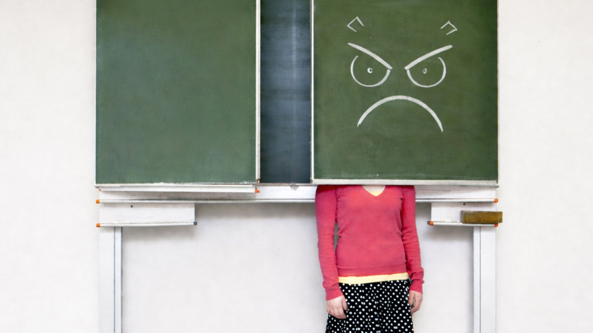 Eine frustrierte Lehrerin versteckt sich hinter einer Tafelklappe