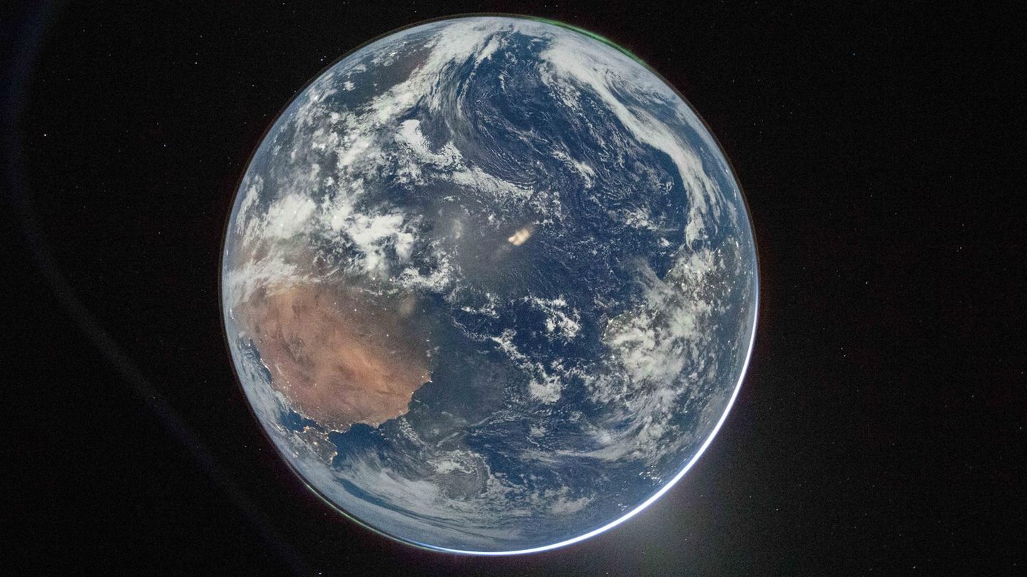 Der blaue Planet in seiner vollen und aus dem Weltall friedlichen Pracht. Während die Erde die Sonne verdeckt, sind oben rechts und unten links Polarlichter zu sehen. Unten rechts an der Erdkugel ist das Zodiaklicht zu sehen – eine Reflexion des Sonnenlichts.