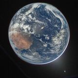 Der blaue Planet in seiner vollen und aus dem Weltall friedlichen Pracht. Während die Erde die Sonne verdeckt, sind oben rechts und unten links Polarlichter zu sehen. Unten rechts an der Erdkugel ist das Zodiaklicht zu sehen – eine Reflexion des Sonnenlichts.