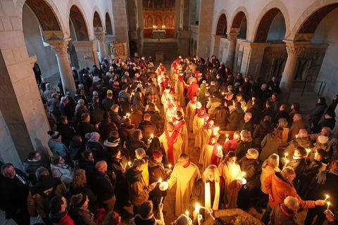Gläubige verteilen das Osterlicht in der Stiftskirche St. Cyriakus. Foto: Matthias Bein/dpa