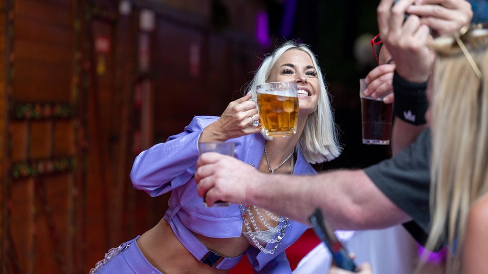 Schlagersängerin Isi Glück prostet mit einem Bier dem Publikum zu